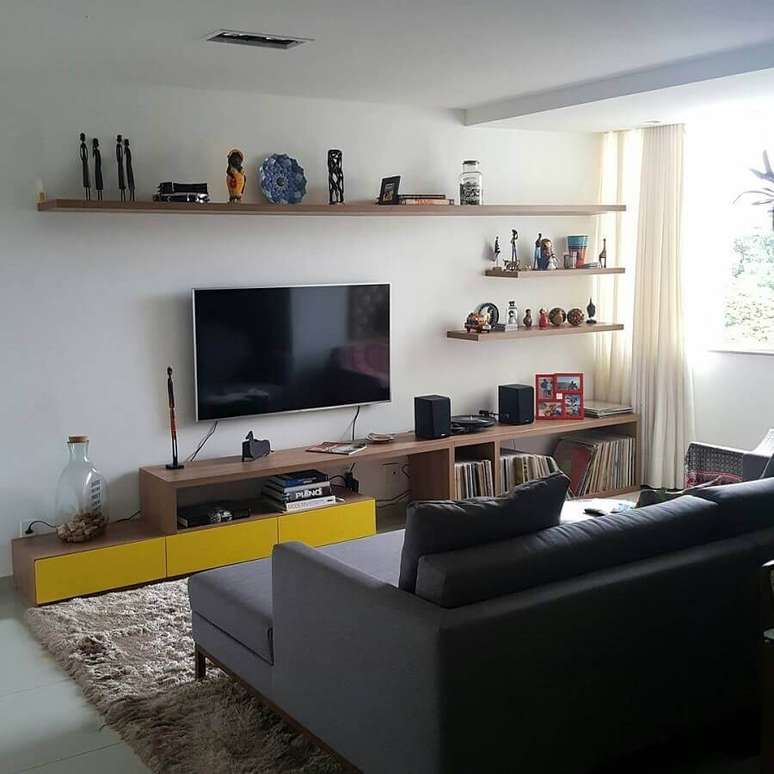 39. Sala simples decorada com sofá cinza e TV na parede com prateleiras de madeira – Foto: Pinterest