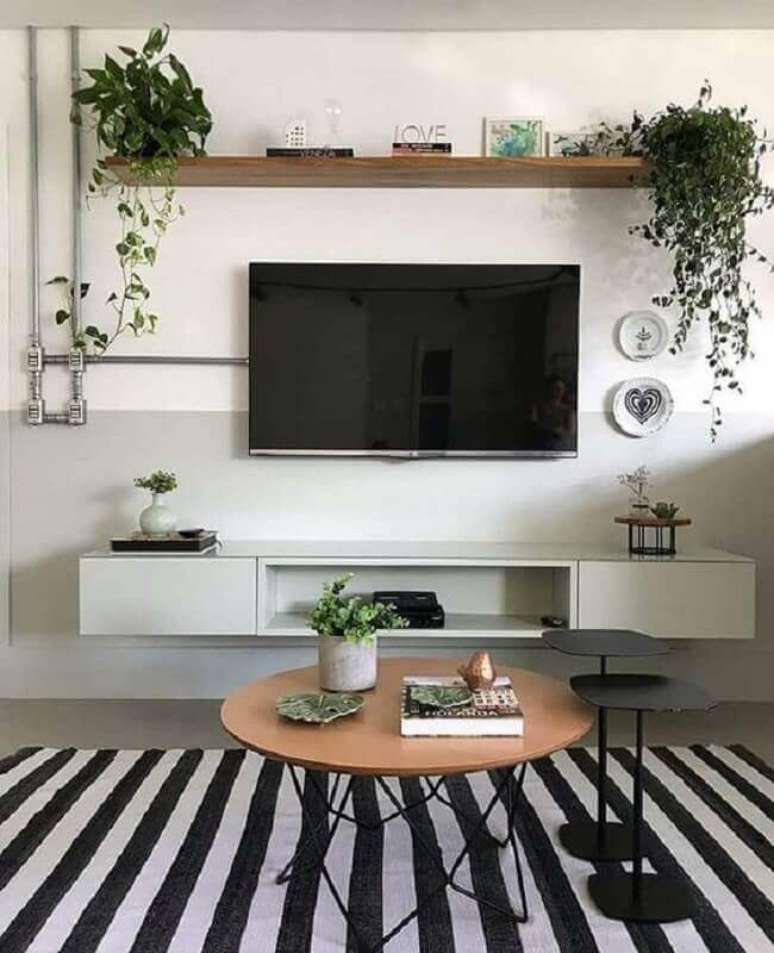43. TV direto na parede de sala cinza e branca decorada com tapete listrado e mesa de centro redonda – Foto: Apartament Therapy