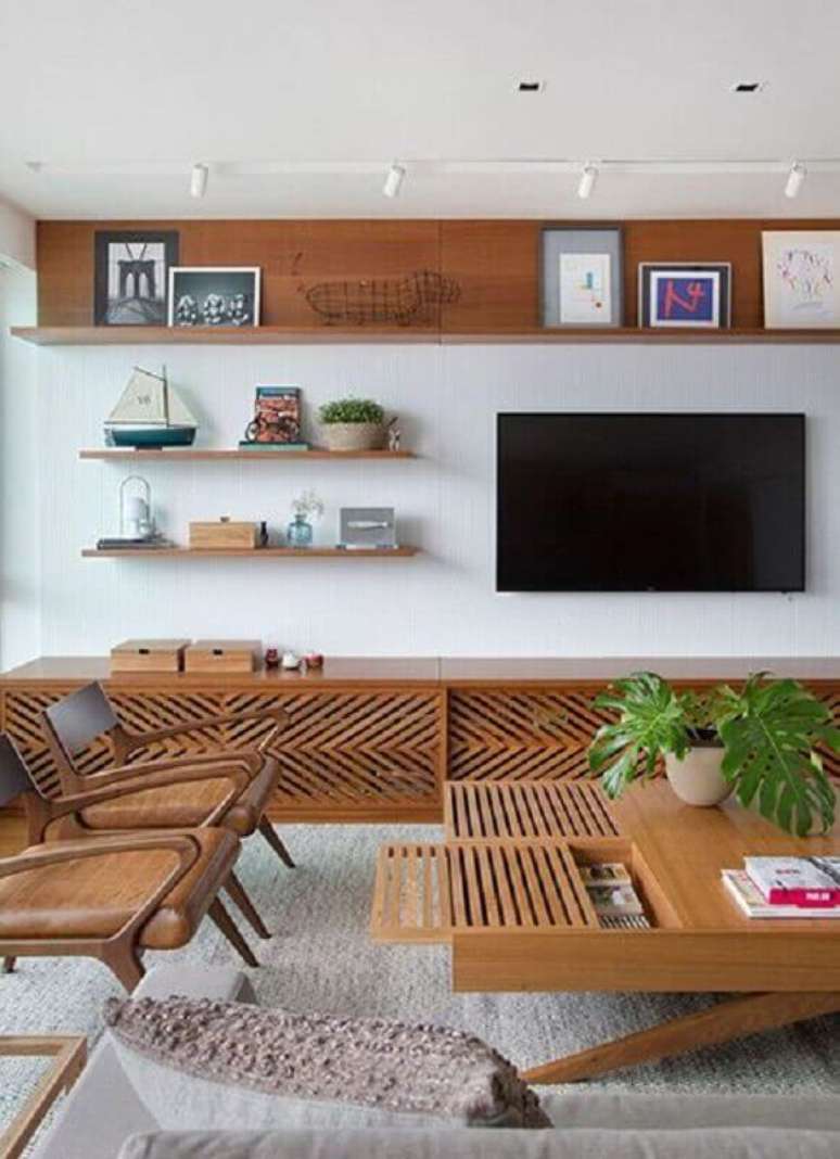 44. Decoração de sala planejada com móveis de madeira e TV na parede sem painel – Foto: Behance
