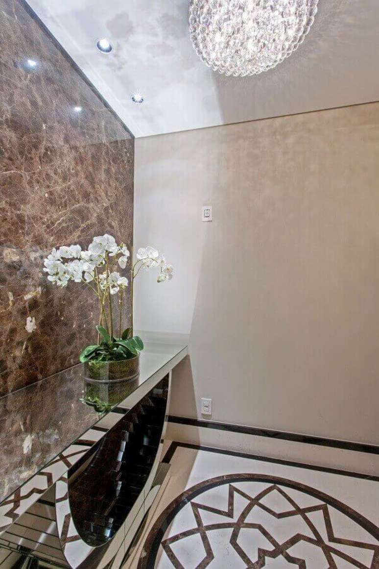 48- Desenho do piso do hall de entrada &eacute; valorizado pelo reflexo no aparador espelhado. Fonte: Iara Kilaris