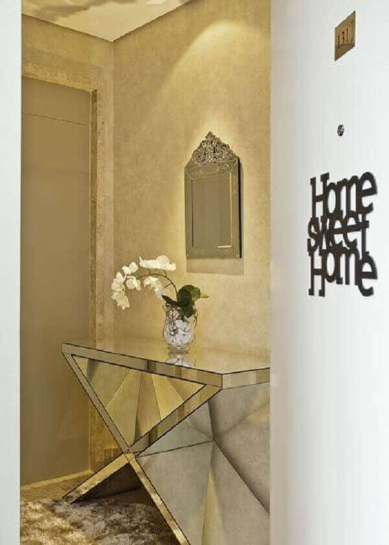 50- O hall de entrada &eacute; decorado com um aparador espelhado com base larga. Fonte: Renata tolentino arquitetura