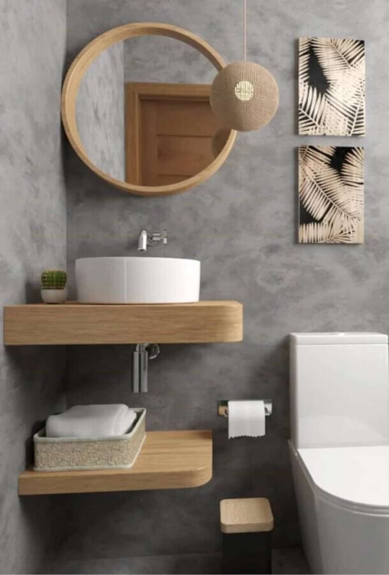28. Banheiro cinza pequeno decorado com bancada suspensa e espelho redondo para banheiro com moldura de madeira – Foto: Artect Arquitetos