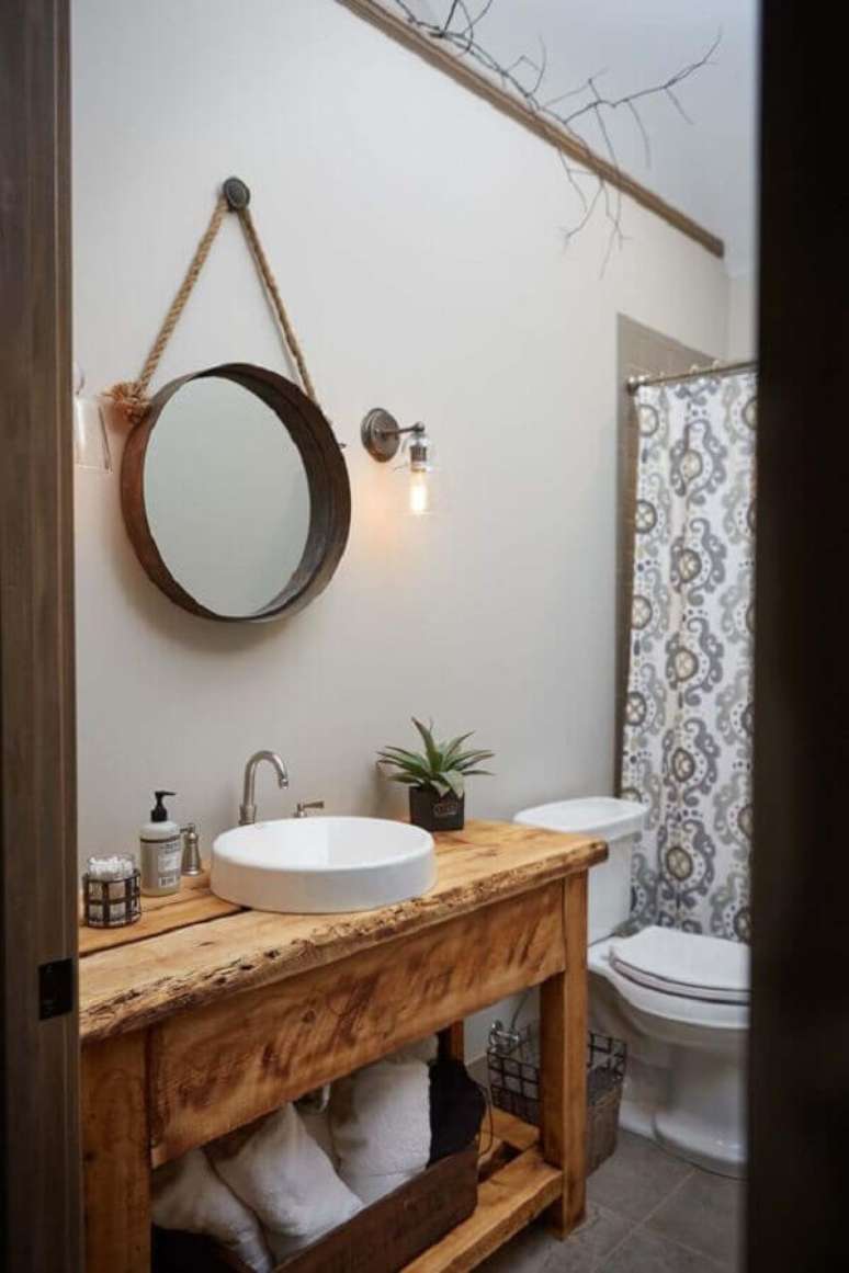 41. Banheiro simples decorado com gabinete rústico e espelho redondo para banheiro com alça de corda – Foto: One Kindesign