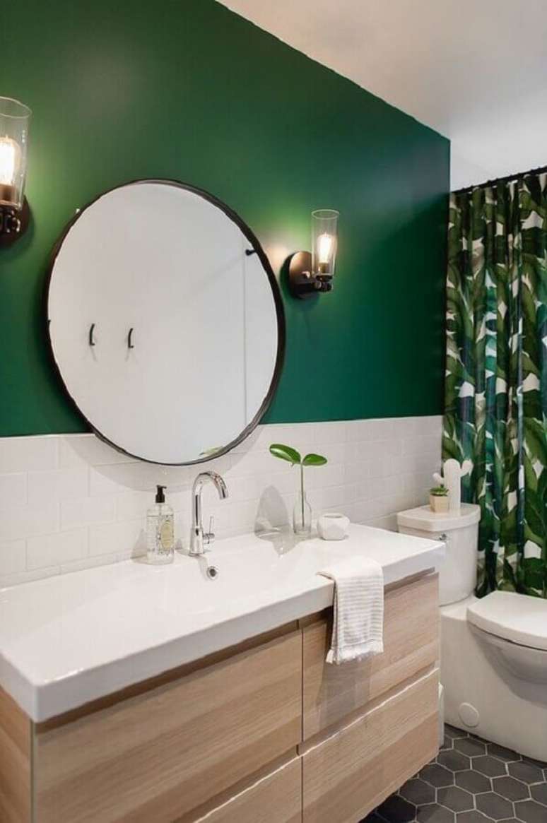 56. Espelho redondo para banheiro decorado com arandela de vidro e parede verde – Foto: Decoist