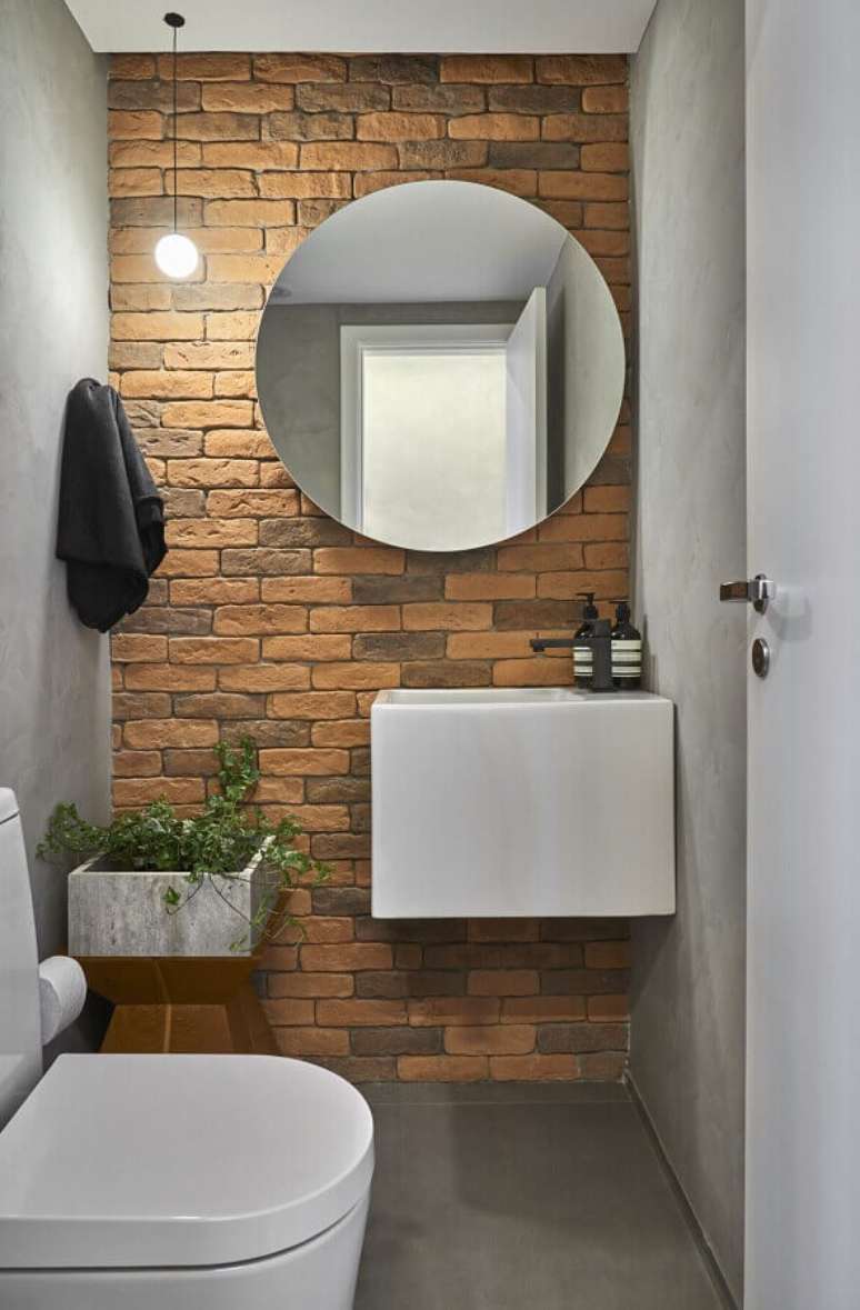 62. Espelho redondo para banheiro pequeno decorado com parede de tijolinho à vista – Foto: Conexão Décor