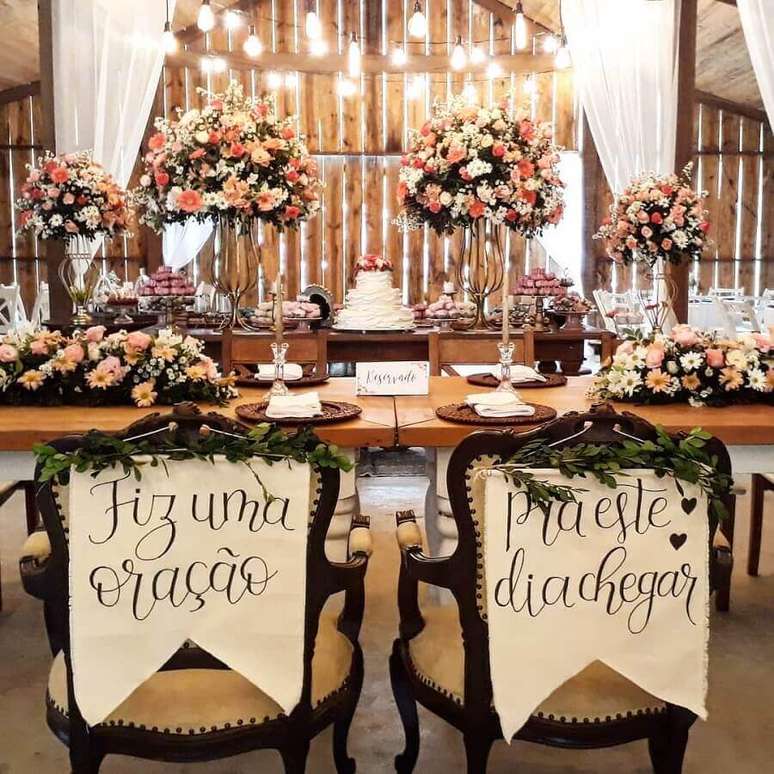 49. Arranjos de flores e cadeiras de noivos personalizadas para decoração de casamento rústico – Foto: Adoletta Festas