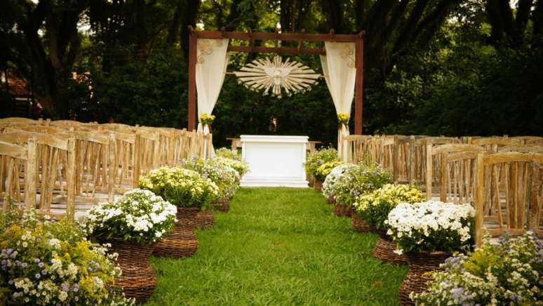 4- Decoração de casamento rústico romântico com flores do campo, tecidos leves e árvores ao fundo.