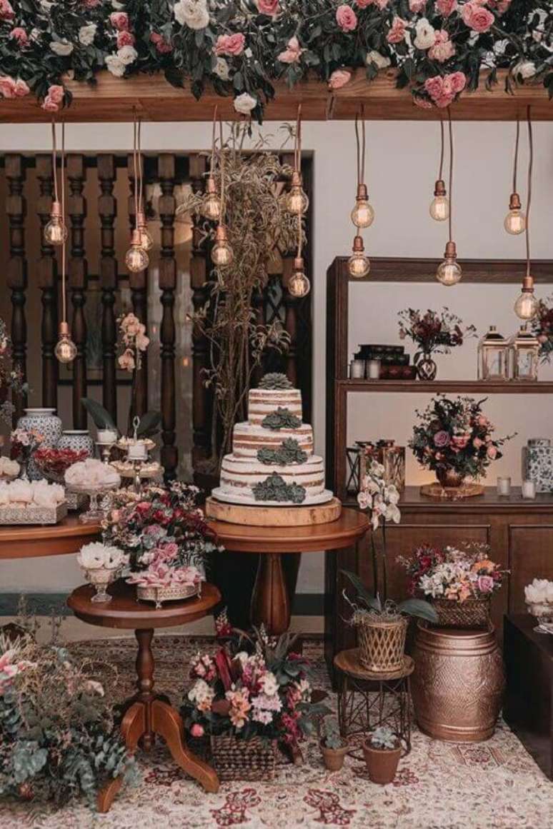 67. Linda decora&ccedil;&atilde;o de mesa de casamento r&uacute;stico com v&aacute;rios arranjos de flores e lumin&aacute;rias pendentes &ndash; Foto: iCasei