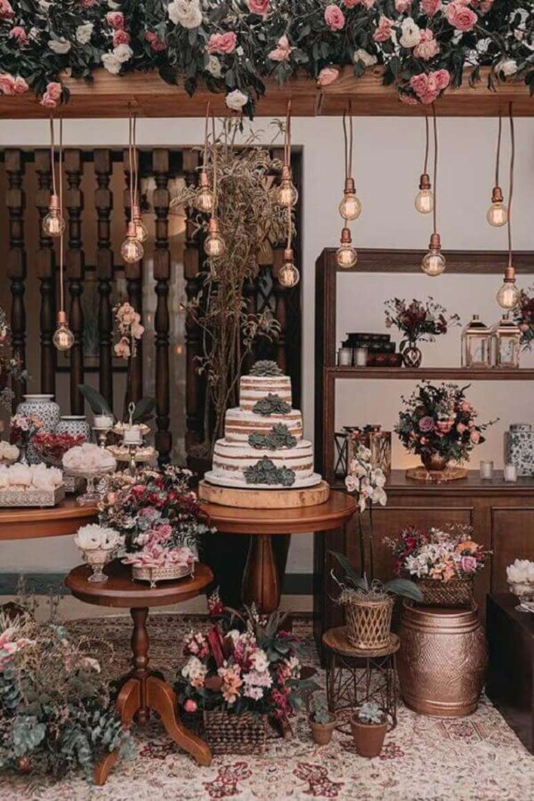 67. Linda decoração de mesa de casamento rústico com vários arranjos de flores e luminárias pendentes – Foto: iCasei