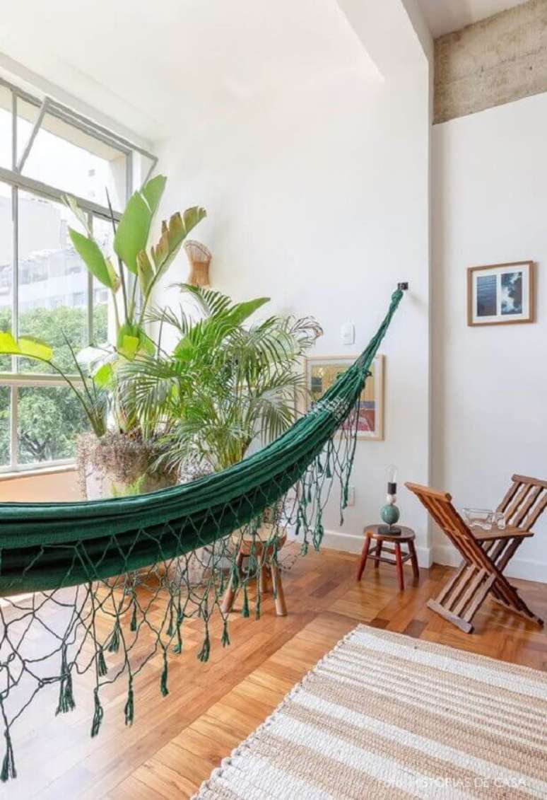 21. Sala decorada com vaso de planta grande e rede de descanso verde – Foto: Histórias de Casa