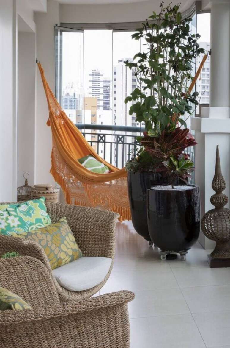 49. Rede de descanso laranja para decoração de varanda com vaso de planta grande e poltronas de fibras naturais – Foto: Conexão Décor