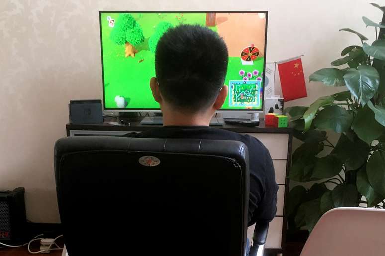 Homem joga o game "Animal Crossing", na China. 24/4/2020. REUTERS/Martin Pollard