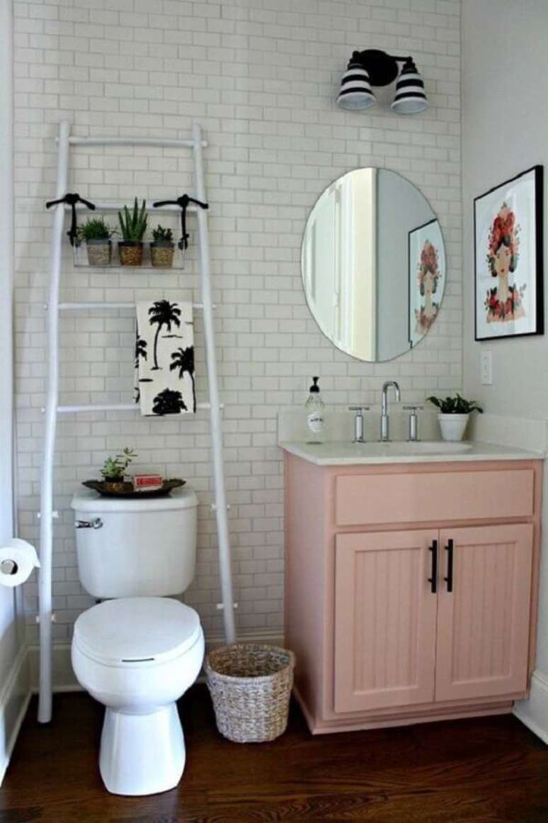 55. Banheiro simples decorado com gabinete rosa e parede de tijolinho branco – Foto: Só Decoração