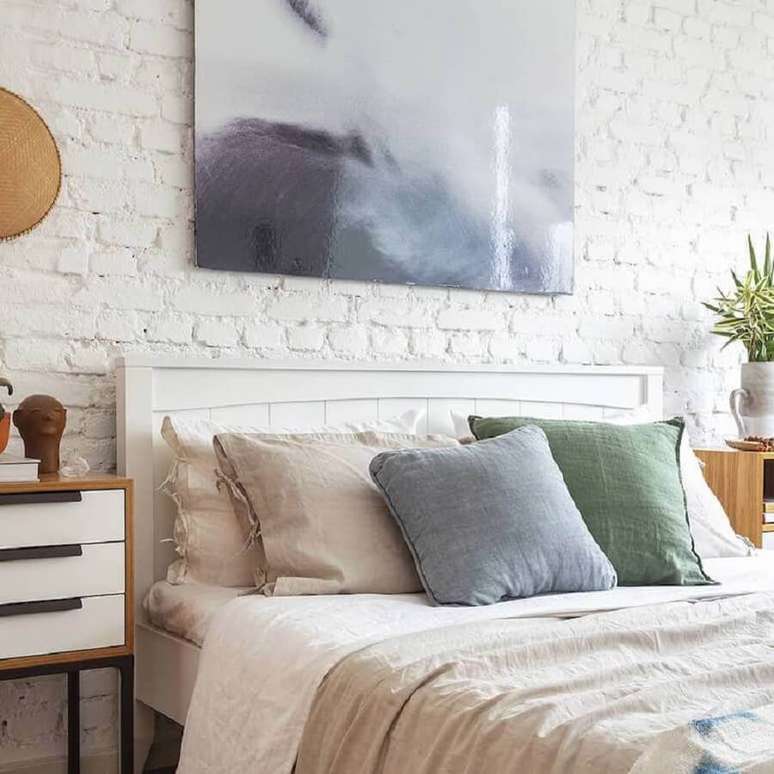 51. Quarto de casal decorado com revestimento tijolinho branco rústico e várias almofadas para cama – Foto: Mooui Home