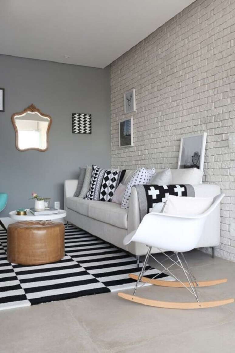 43. Parede de tijolinho branco para decoração de sala de estar com tapete preto e branco e cadeira eames de balanço – Foto: Futurist Architecture