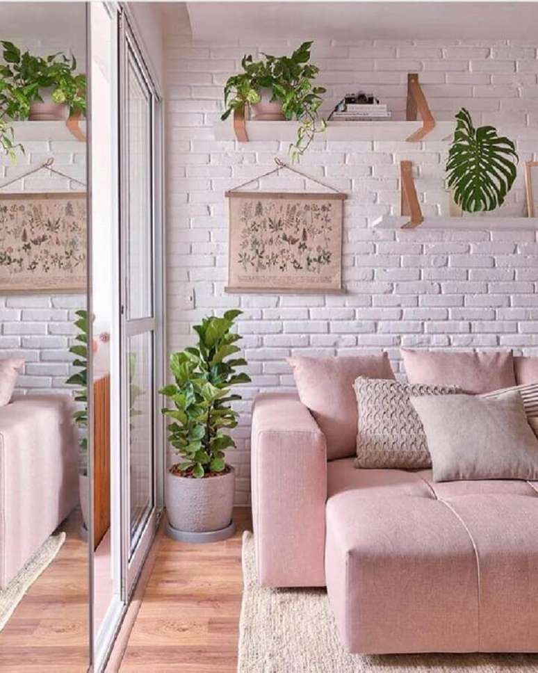 12. Delicada decoração de sala com sofá rosa e prateleiras para plantas em parede de tijolinho branco – Foto: Pinterest