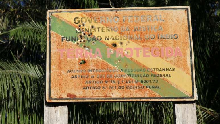 Esta placa crivada de balas na fronteira de uma reserva indígena no Brasil é uma evidência do aumento das tensões