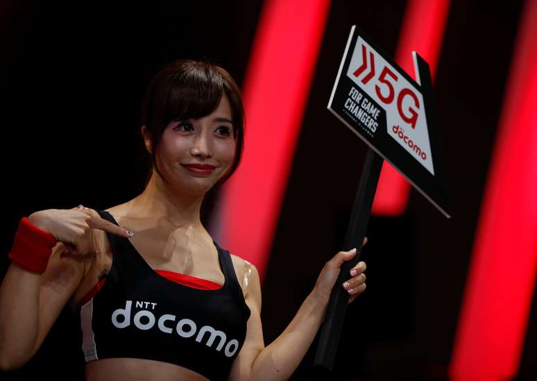 AMulher mostra placa com anúncio da NTT Docomo sobre tecnologia 5G. 12/9/2019. REUTERS/Issei Kato