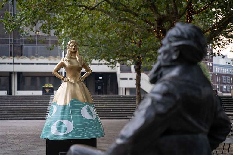 Frances Dickens em frente à estátua de seu irmão Charles em Portsmouth, Inglaterra, sua cidade natal