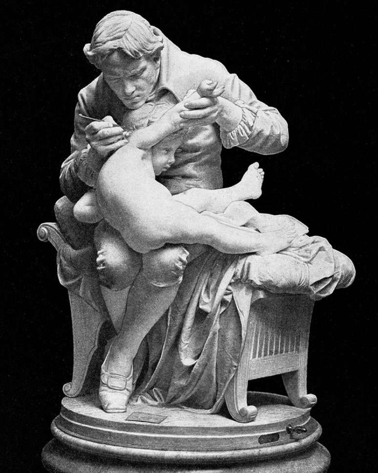 Experimento de Edward Jenner, eternizado nesta est&aacute;tua vacinando o pr&oacute;prio filho, usava v&iacute;rus da var&iacute;ola bovina