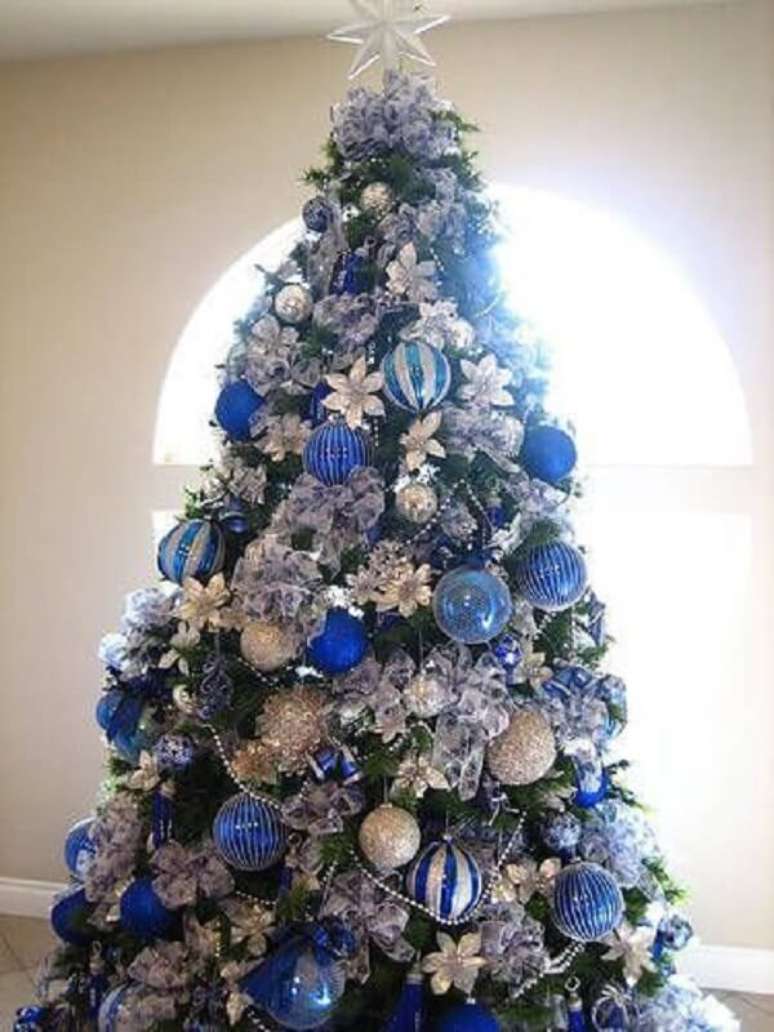 19. A majestosa &aacute;rvore de natal decorada azul e prata foi posicionada pr&oacute;xima a janela. Fonte: Pinterest