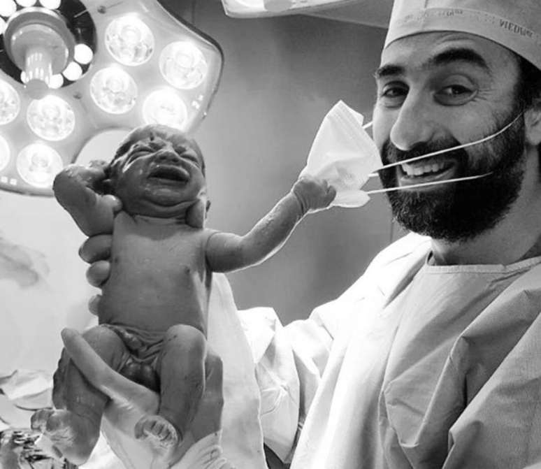 Uma foto que mostra um recém-nascido puxando a máscara de um médico viralizou nas redes sociais