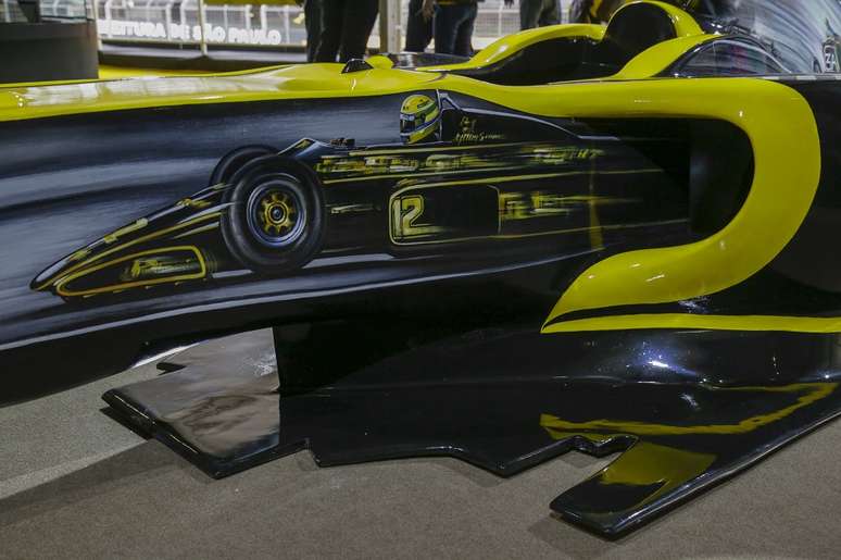 Imagem de Ayrton Senna com o Lotus Renault de 1985 aparece na lateral esquerda carro.