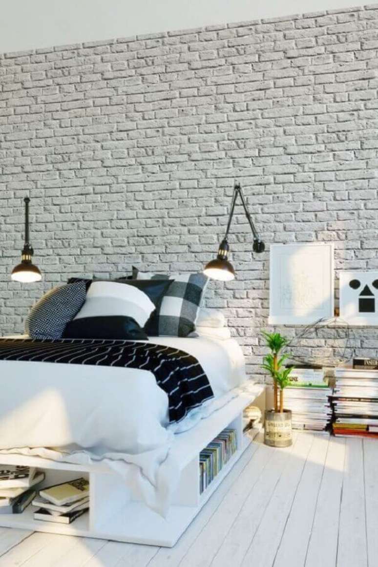 26. Luminária de cabeceira para leitura em quarto de casal decorado com várias almofadas e parede de tijolinho branca – Foto: Parachute