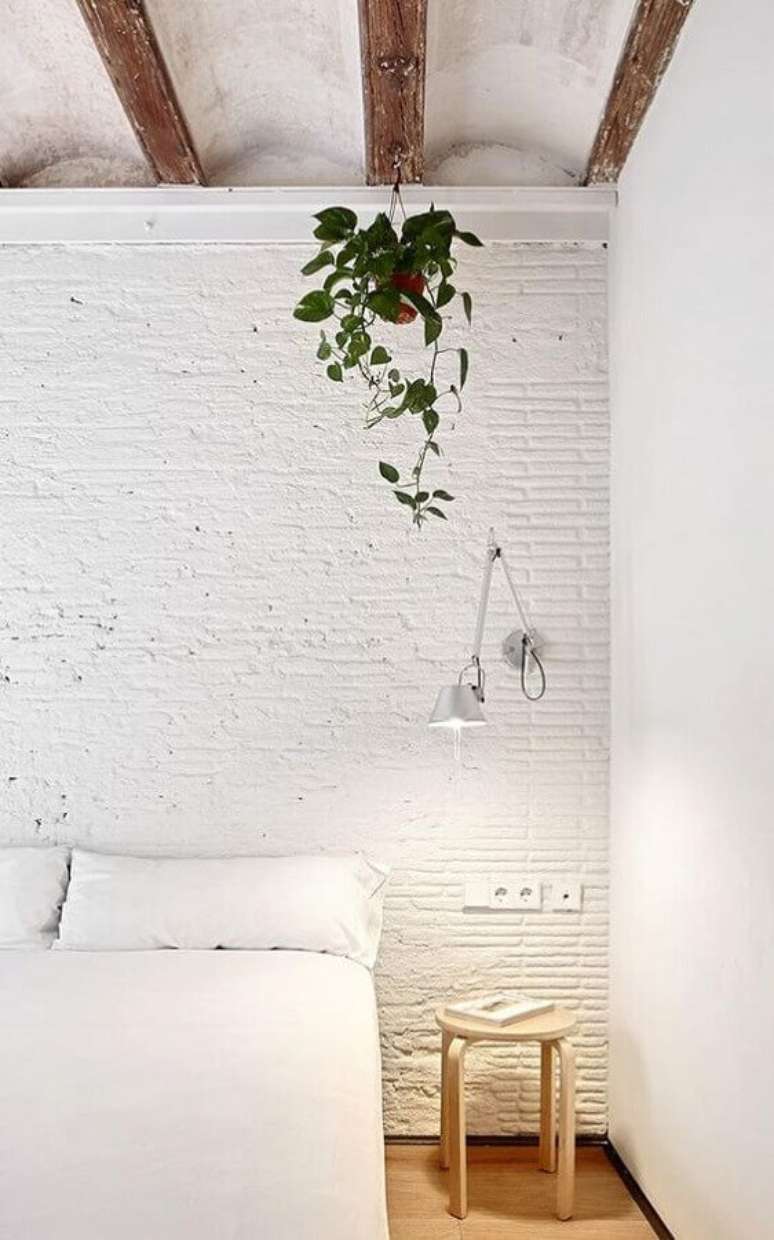 46. Quarto branco com parede de tijolinho rústica decorado com luminária de cabeceira articulada para leitura – Foto: HomeWorldDesign