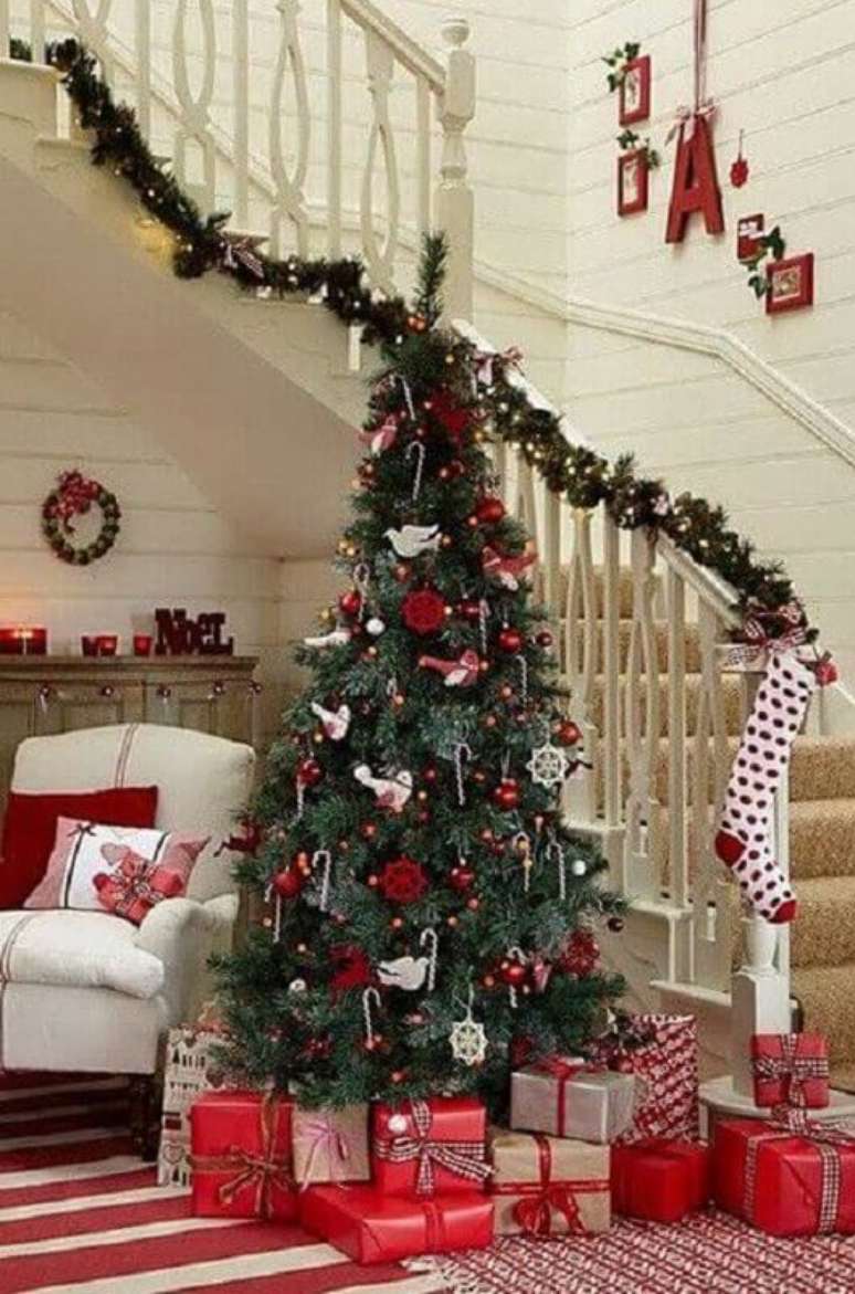 19. Sala decorada com árvore natalina e festão de Natal verde para escada – Foto: Elle Decor
