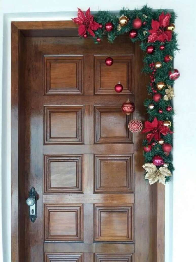 36. Festão de Natal verde decorado com flores e bolas douradas e vermelhas para porta – Foto: Muito Chique