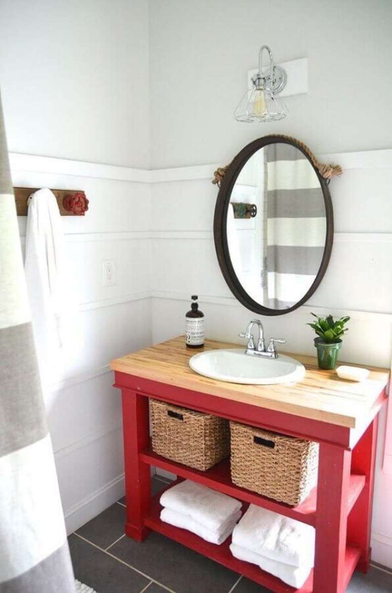 59. Decoração de banheiro vermelho e branco simples com bancada de madeira e espelho redondo – Foto: Planeta Design