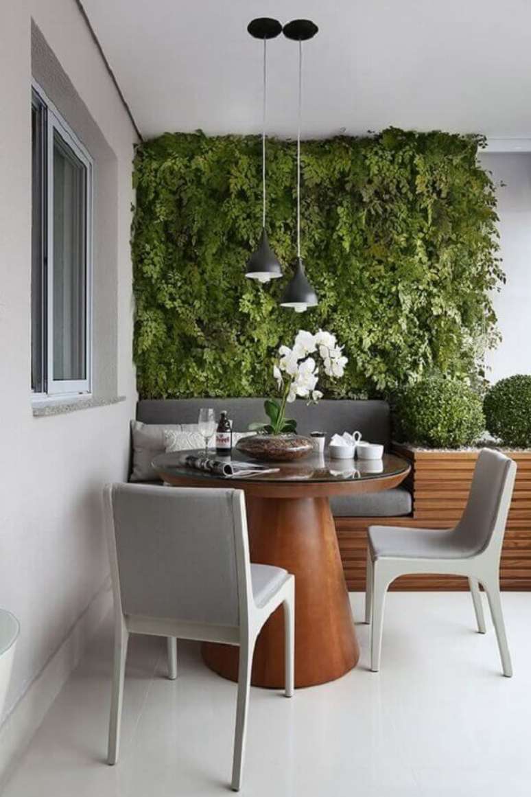 15. Plantas para varanda cinza moderna decorada com mesa redonda de madeira e jardim vertical – Foto: Mariana Orsi