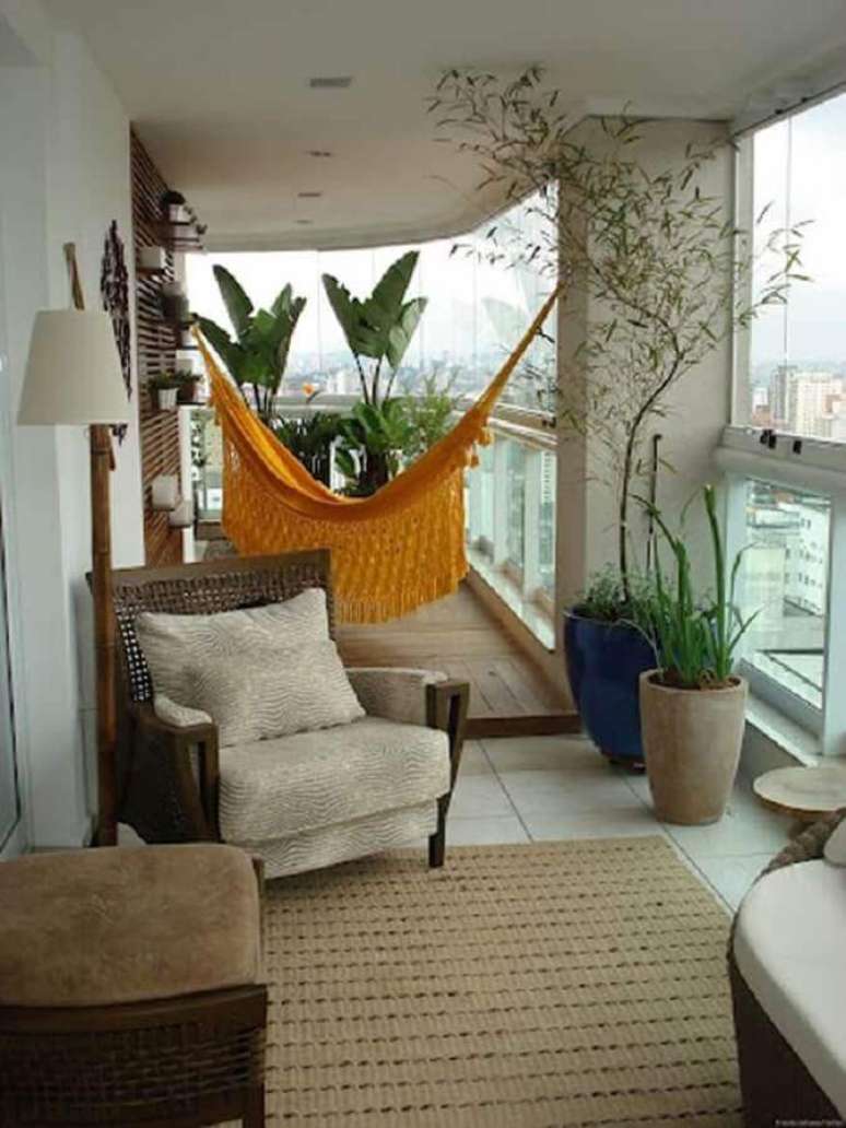 32. Decoração com rede amarela e vasos de plantas para varanda de apartamento – Foto: Histórias de Casa