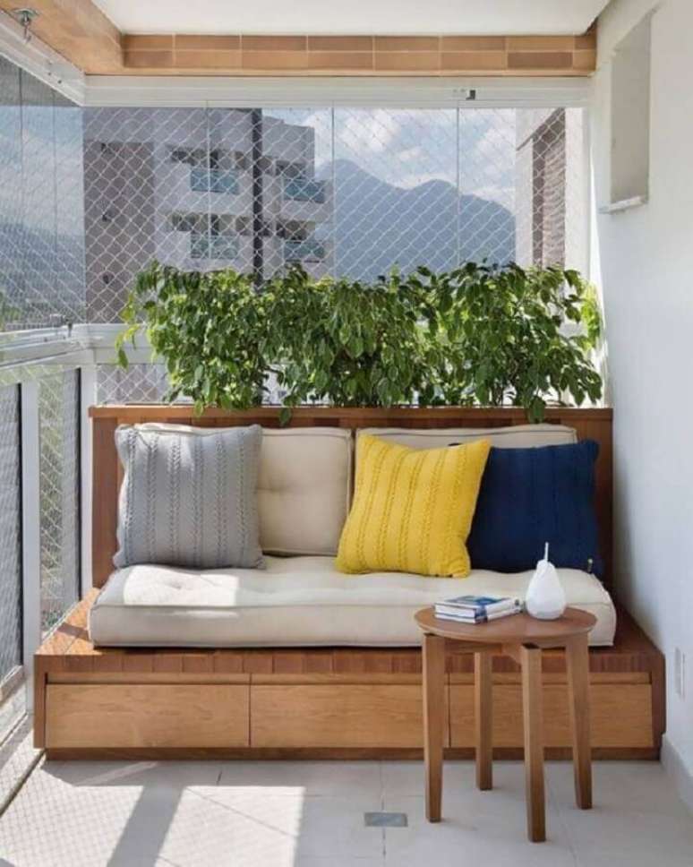 33. Plantas para varanda com sol decorada com banco de madeira e almofadas coloridas – Foto: Simples Decoração