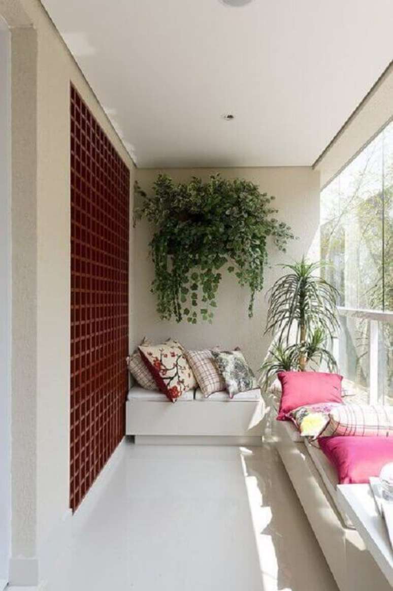 34. Decoração simples com plantas para varanda e bancos brancos com almofadas coloridas – Foto: Arquitrecos