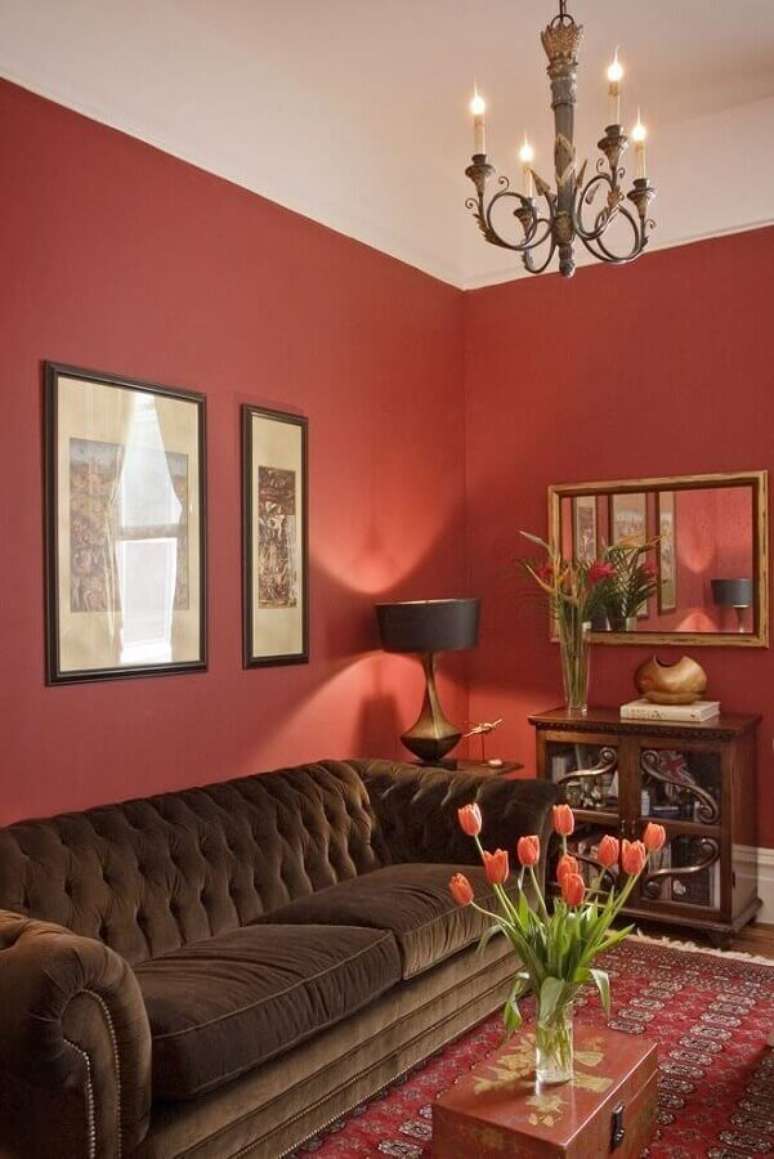 60. Sala vermelha decorada com lustre clássico e sofá marrom escuro com acabamento capitonê – Foto: Pinterest