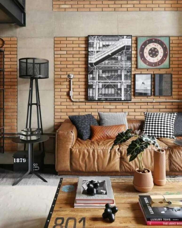 65. Sala com estilo industrial decorada com parede de tijolinho e sofá marrom claro com várias almofadas – Foto: Futurist Architecture