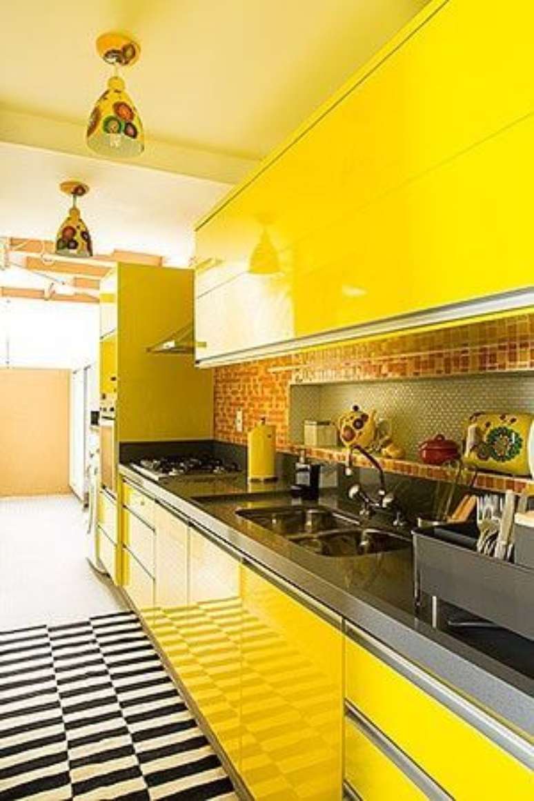 39. Armário de cozinha amarelo com tapete preto e branco – Via: Casa e Jardim