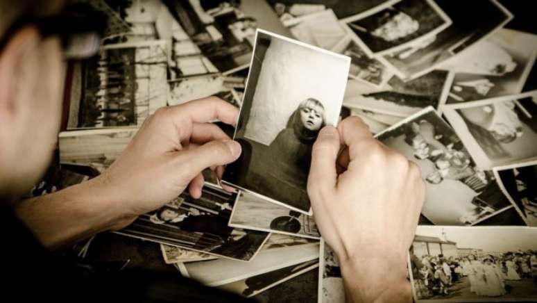 Homem examina coleção de fotos antigas (Imagem: jarmoluk/Pixabay)
