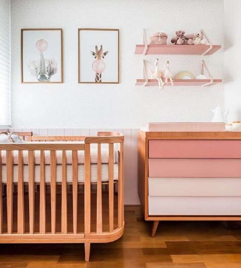44. Decoração delicada com berço de madeira, poltrona com gavetas cor de rosa e quadros para quarto de bebê feminino – Foto: Vobibr