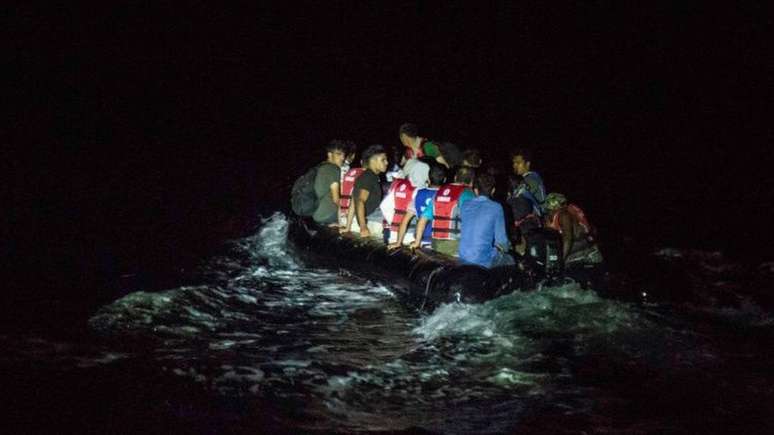 Um bote de borracha cheio de migrantes atravessa a ilha grega de Lesvos à noite - uma das rotas favoritas para os migrantes afegãos entrarem na Europa