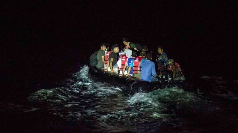 Um bote de borracha cheio de migrantes atravessa a ilha grega de Lesvos &agrave; noite - uma das rotas favoritas para os migrantes afeg&atilde;os entrarem na Europa