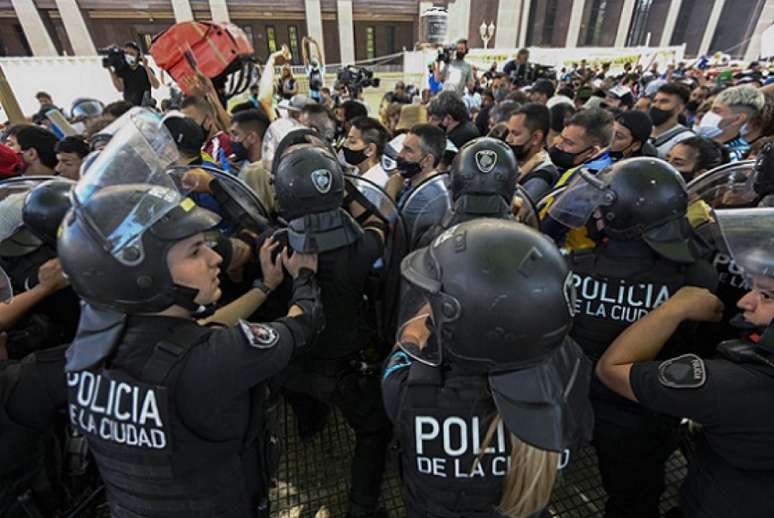 Policiais tentam dispersar os torcedores (Foto: JUAN MABROMATA / AFP)