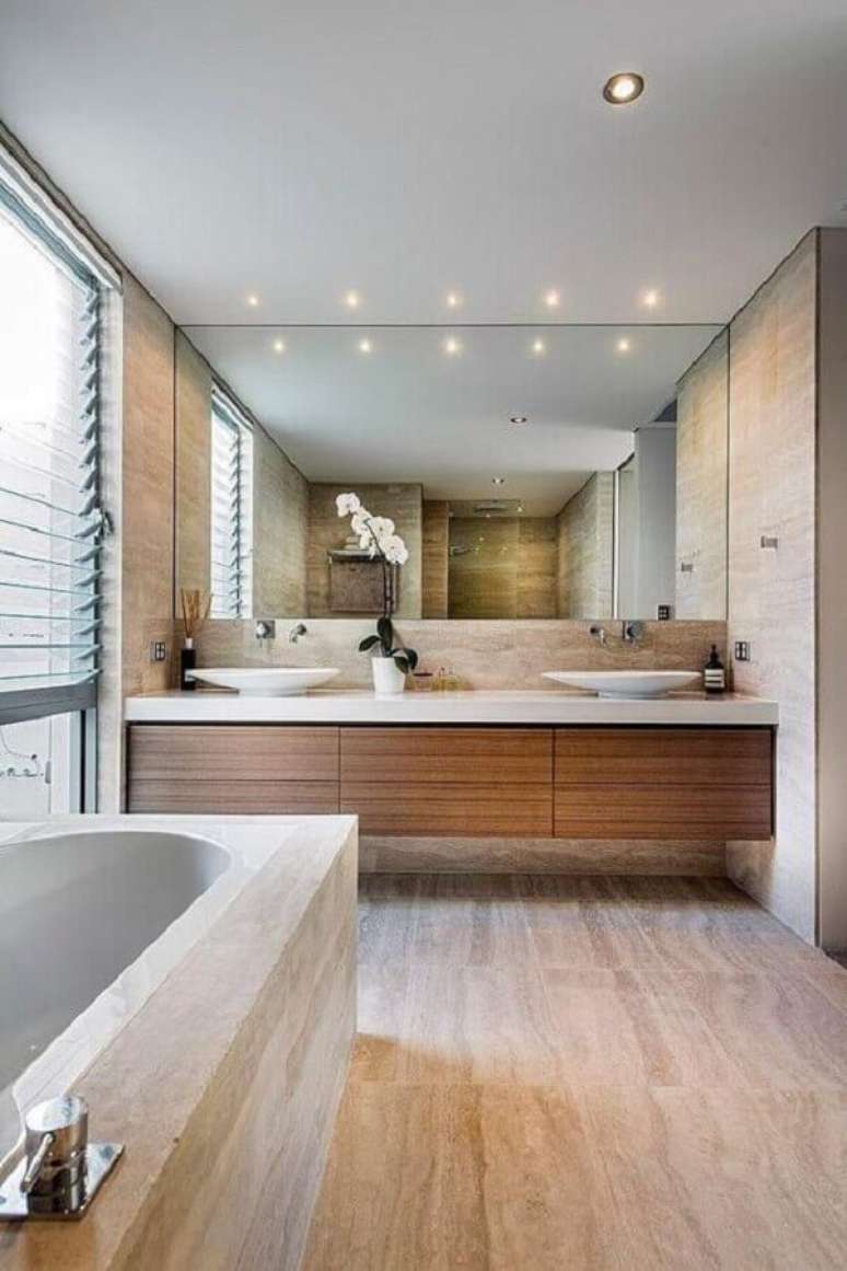 30. Decoração de banheiro sob medida amplo com gabinete de madeira e banheira – Foto: Decostore