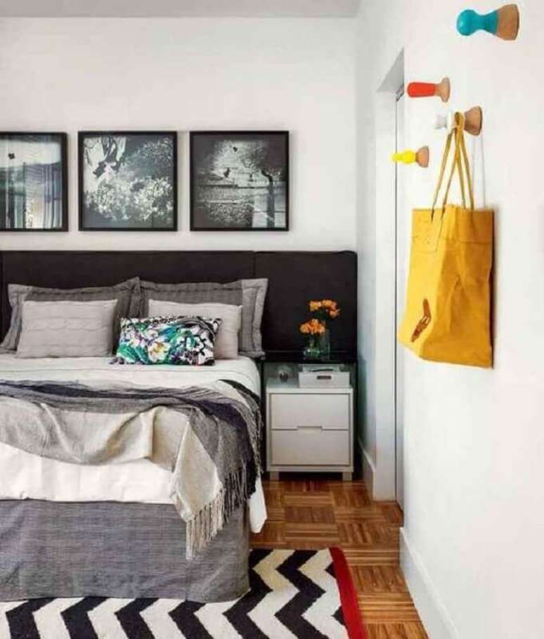 39. Quarto simples decorado com cabeceira preta planejada e quadros na parede – Foto: Jeito de Casa