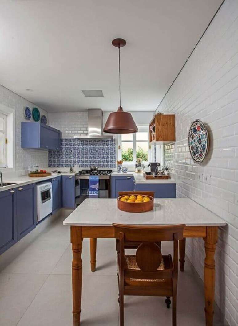 41. Cozinha decorada com mesa de madeira quadrada e armário de cozinha planejado azul de canto – Foto: Casa de Valentina