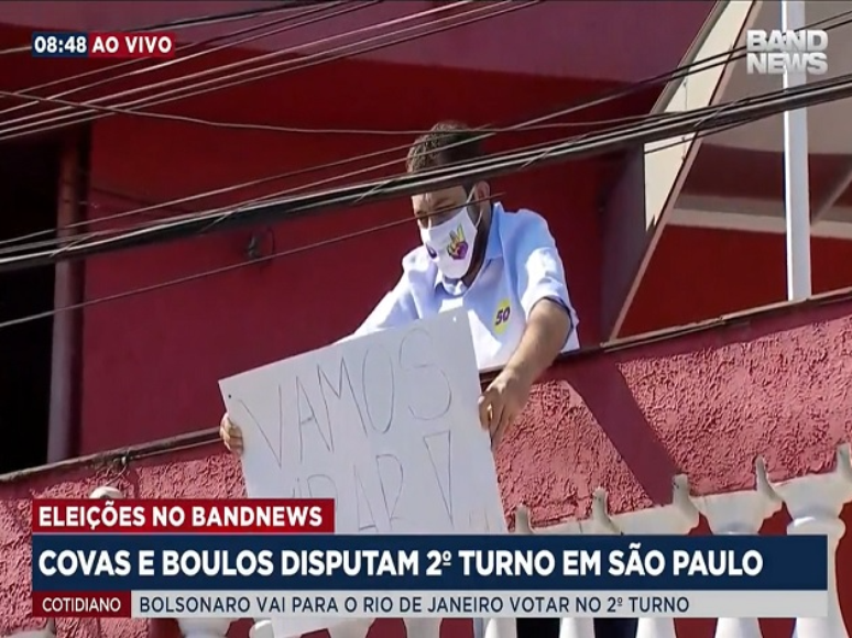 Boulos segura cartaz na sacada da sua casa