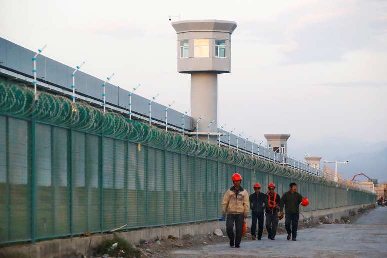 Trabalhadores caminham ao lado de cerca do que é oficialmente chamado de centro educacional de habilidades vocacionais em Dabancheng, na região chinesa de Xinjiang
04/09/2018 REUTERS/Thomas Peter