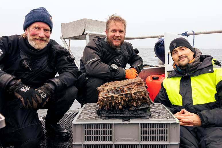 Da esquerda para a direita, os arqueólogos submarinos Christian Howe, Florian Huber and Uli Kunz posam para foto com a máquina Enigma encontrada por eles
11/11/2020
REUTERS/Christian Howe
